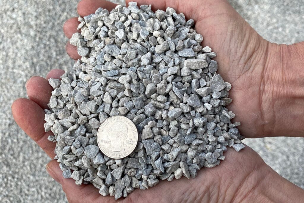 #9 Limestone — small clean grey limestone chip held in a hand with a quarter for scale