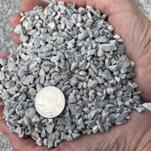 #9 Limestone — small clean grey limestone chip held in a hand with a quarter for scale